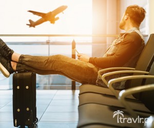 Mężczyzna na lotnisku czeka na lot z nogami na walizce