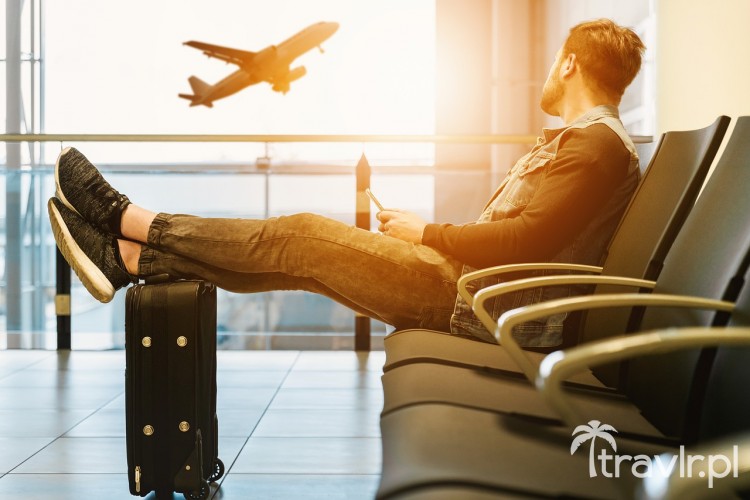 Mężczyzna na lotnisku czeka na lot z nogami na walizce