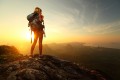 Turysta z plecakiem na szczycie góry o wschodzie słońca