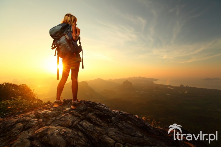 Turysta z plecakiem na szczycie góry o wschodzie słońca
